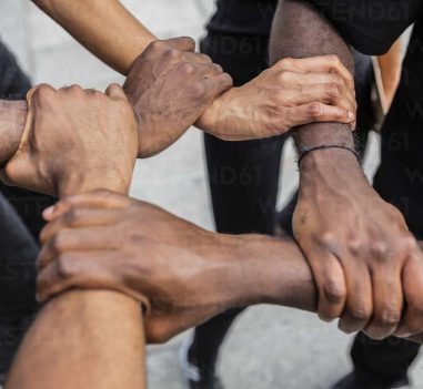 From above of crop anonymous African American partners holding hands demonstrating unity symbol in town